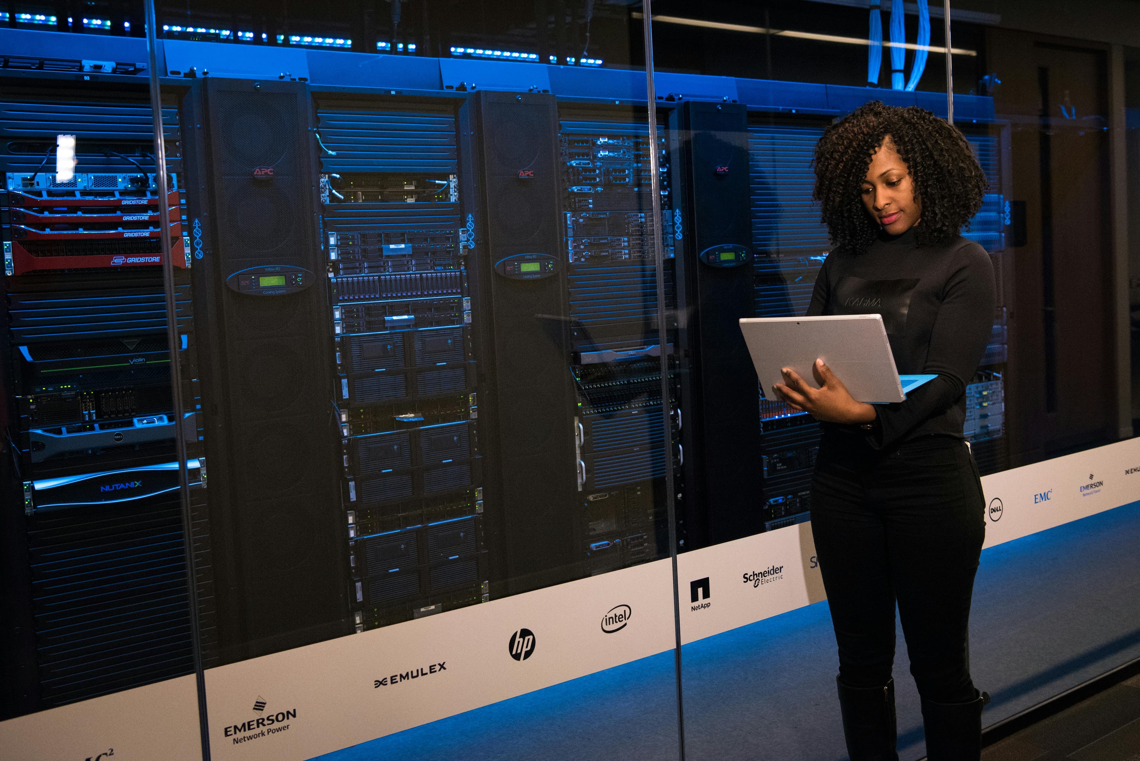 A DevOps engineer using a tablet in a data center while reviewing deployment systems.