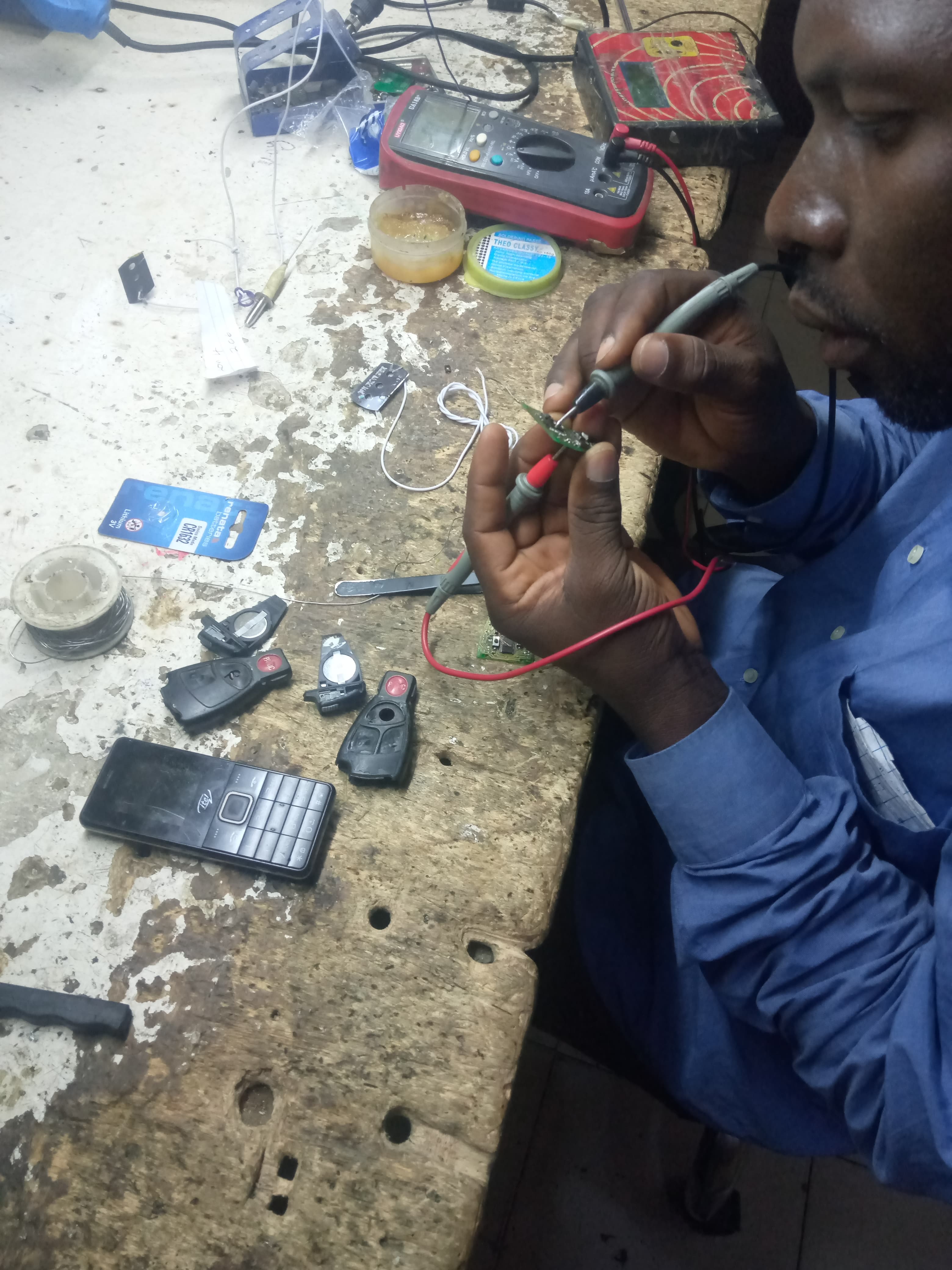 Technician diagnosing a small electronics board with test leads.