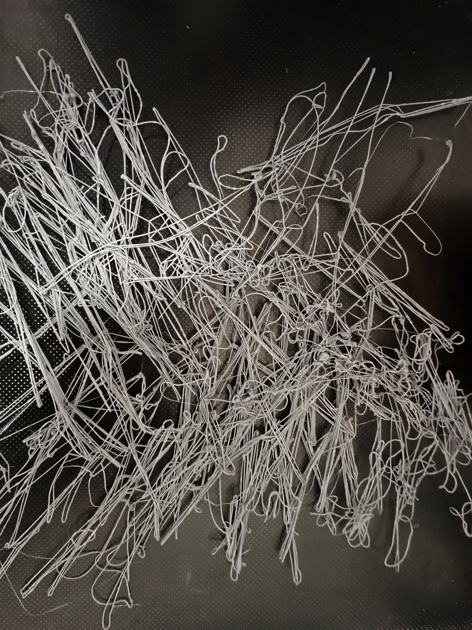 A failed 3D print with tangled filament across the build plate.