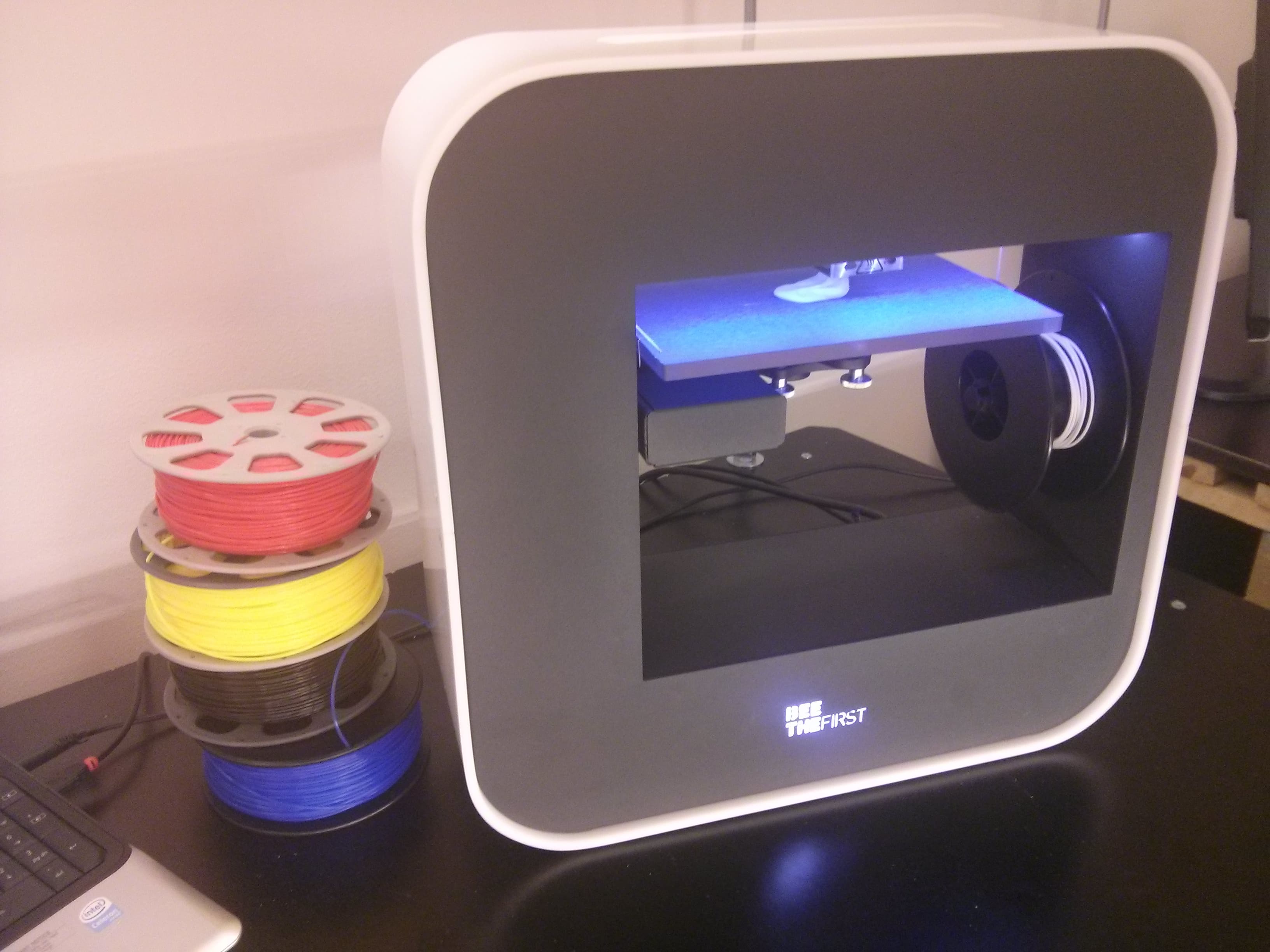 3D printer with stacked colorful filament spools.